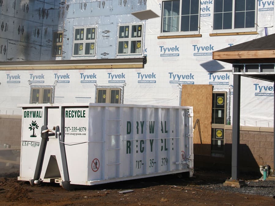 A drywall recycling container for contractors sitting outside of an in-progress building